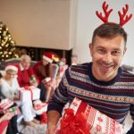 A father holding Christmas gifts smiling