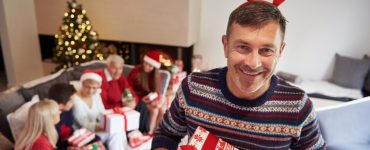 A father holding Christmas gifts smiling