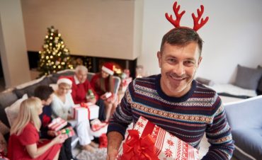 A father holding Christmas gifts smiling