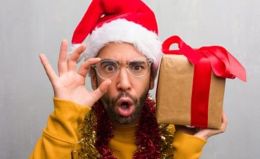 Man Holding Christmas Gifts And Santa Hat
