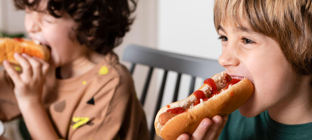 two children eating hotdogs