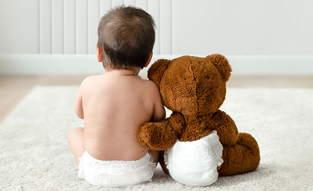 baby sitting next to teddy bear